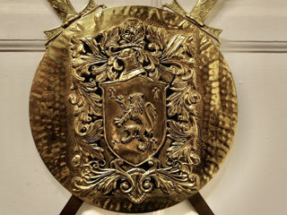 Старинный бронзовый геральдический щит с безудержным львом и скрещенными мечами.