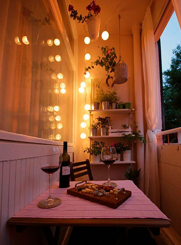Decor iluminat la balcon si o masuta cu 2 pahare de vin