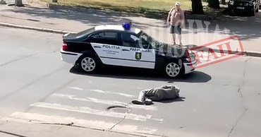 В Кишиневе машина полиции объехала мужчину, лежащего поперек дороги.
