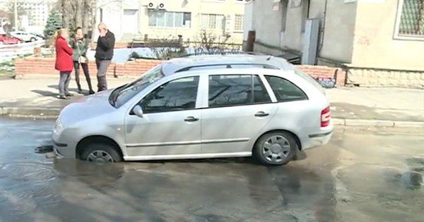 Maşină blocată într-o gaură formată în asfalt pe o stradă din Capitală. Foto: Captură video