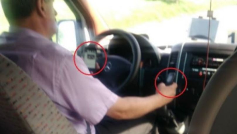 Un șofer de microbuz, filmat cu două telefoane în mâini, la volan