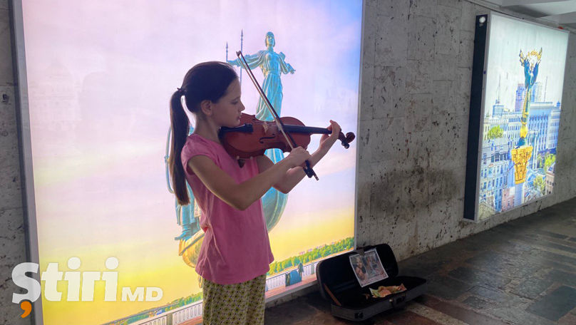 O fată cântă la vioară într-o subterană pentru a ajuta o fostă colegă