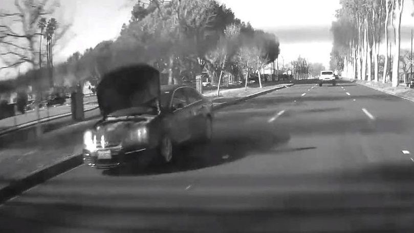 Черный седан едет с открытым капотом, полностью перекрывшим обзор.