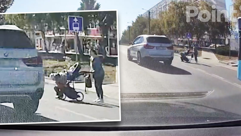 O femeie cu un bebeluș în cărucior, la un pas de a fi spulberată de un BMW.