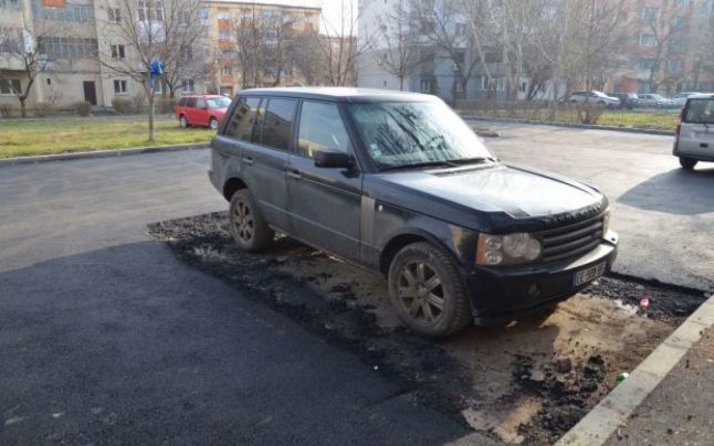 Muncitorii au asfaltat o parcare în jurul unui autoturism. 