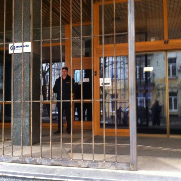 На улице у здания стоят два бойца «неизвестного батальона», а внутри сквозь затемненные окна видно еще с десяток бойцов.