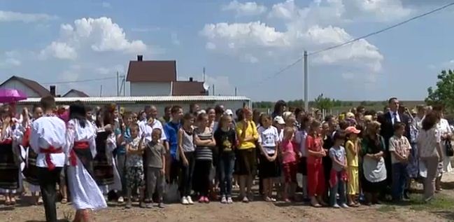 Десятки сельчан собрались 22 мая у импровизированной сцены, где вручали документы на новые дома последним пострадавшим от наводнения 2010 года. 