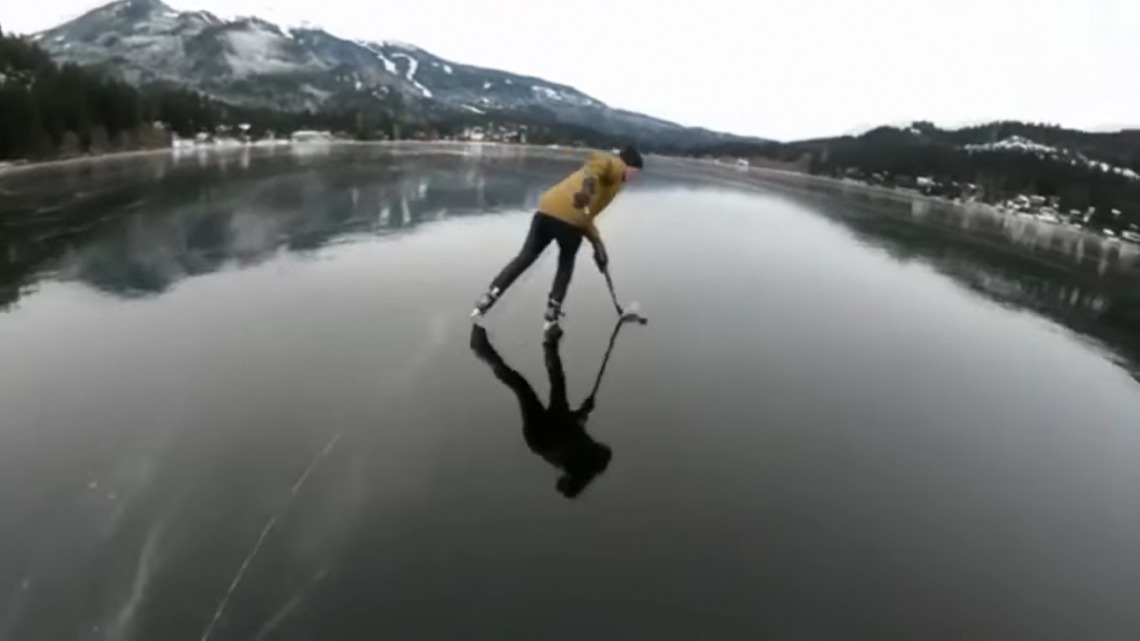 Doi tineri joacă hochei pe un lac înghețat.