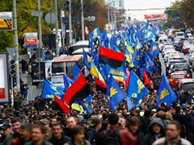 В колонне идут представители и сторонники ВО "Свобода" с партийными флагами, Государственными флагами и плакатами.