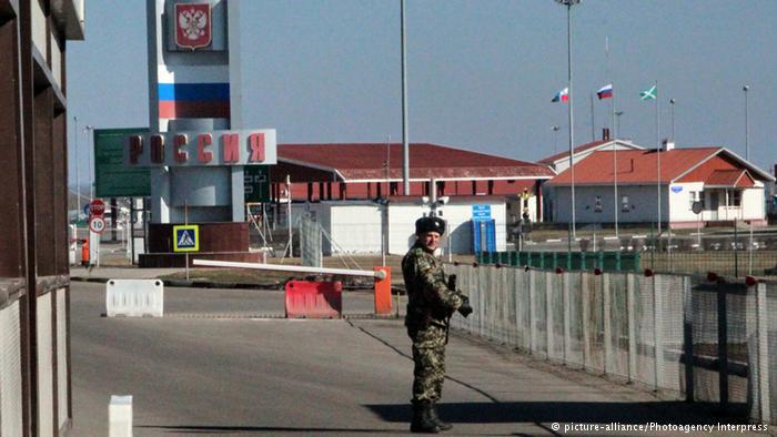 Люди пересекают границу в обоих направлениях, двигаясь поодиночке или группами.