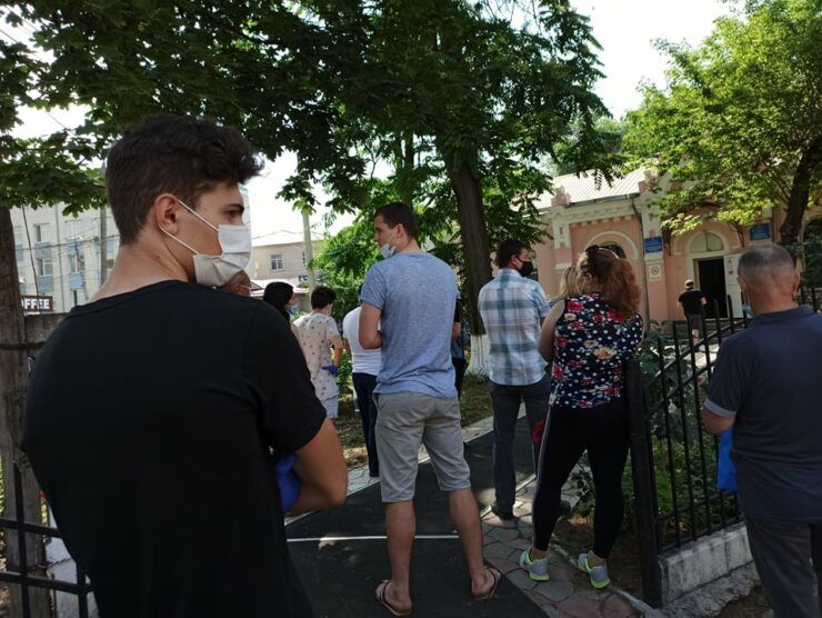 Люди стоят в очереди у наркодиспансера, чтобы оформить документы на водительские права. Фото: zdg.md