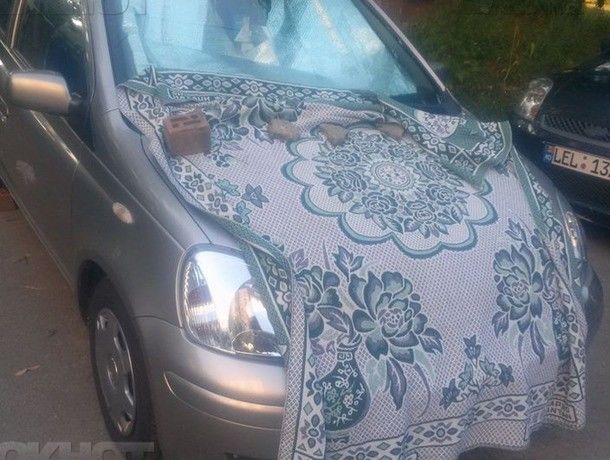 Proprietarul unei mașini din capitală își apără mașina de furtună cu o pătură.