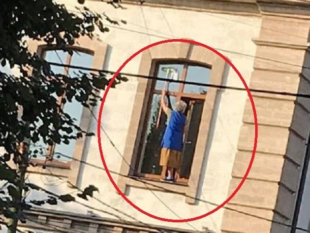Бесстрашная уборщица ГУМ мыла окна шваброй, стоя на подоконнике.