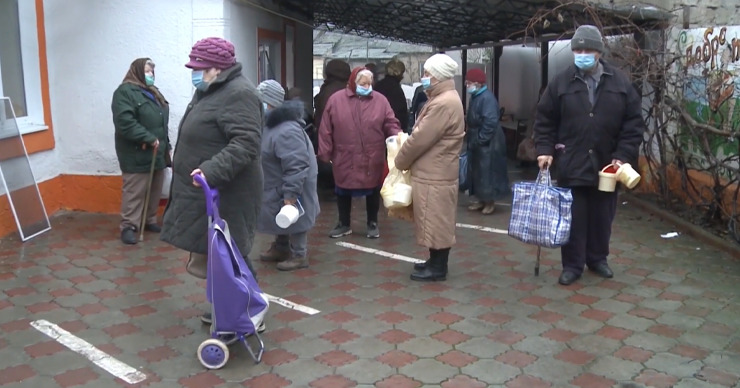 В столице пожилые люди стоят в очереди, чтобы бесплатно взять еду в столовой.