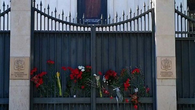 Жители Мадрида несут цветы и игрушки к российскому посольству.