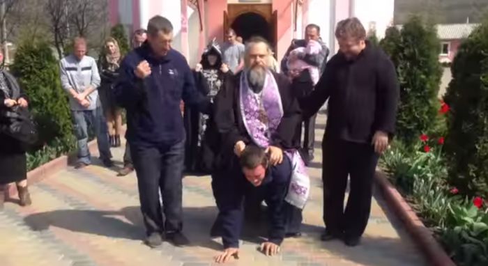 Într-un ritual de exorcizare straniu, preotul practic îl încalecă pe un bărbat și îl calcă în picioare.