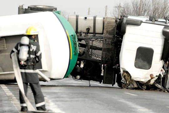 Echipele de intervenţie depun eforturi pentru a ridica autocamionul de pe traseu cu ajutorul unei macarale.