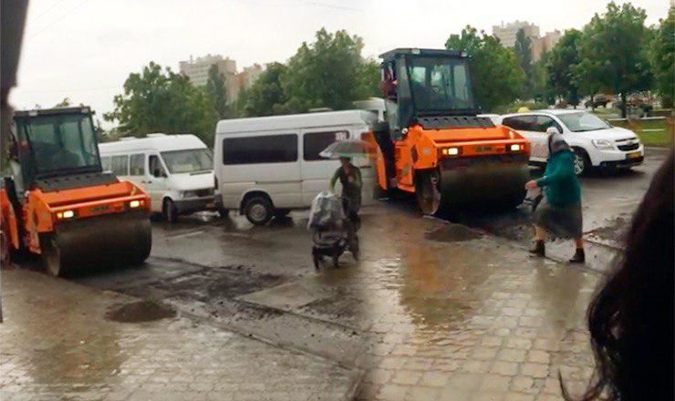 На Чеканах рабочие асфальтировали дорогу во время дождя.