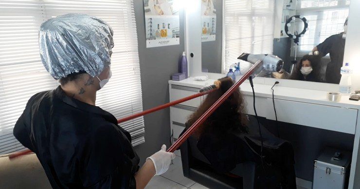 В Бразилии парикмахер сделала укладку клиентке на расстоянии из-за COVID-19.