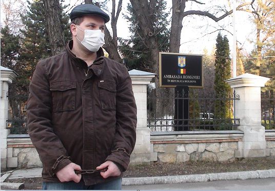 Supărat că redobândirea cetățeniei române nu e accesibilă pentru cei cu venituri reduse, un moldovean și-a legat lanțuri de mâini și picioare. Foto: politik.md