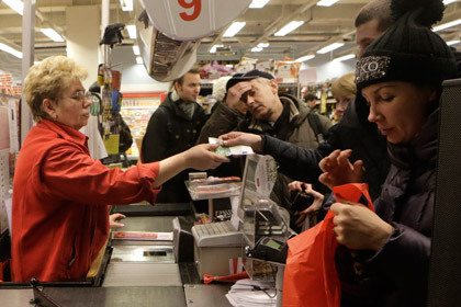 Покупатель расплачивается банкнотой евро в магазине Риги. Фото: Ints Kalnins / Reuters