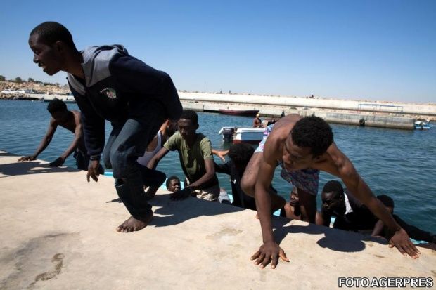 Momentul în care o barcă cu imigranţi ajunge pe o plajă plină de turişti. Foto: Agerpres