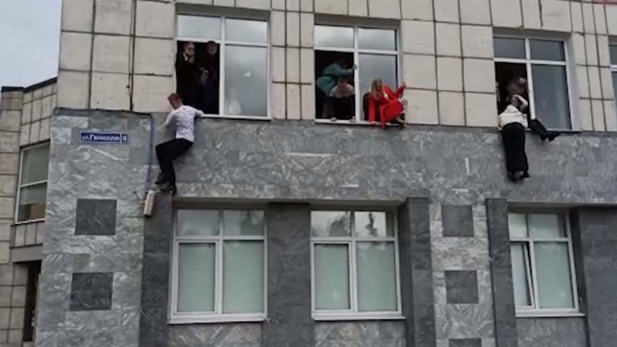 Молодые люди выпрыгивают из окон здания.