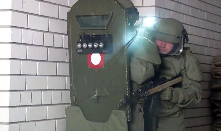 Боец, держащий в руке бронещит с часто мигающими фонарями.