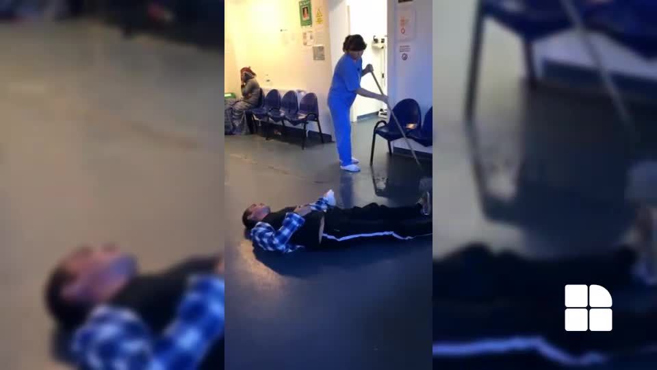 O infirmieră şterge cu mopul pe lângă un pacient căzut pe podea. Foto: captură video