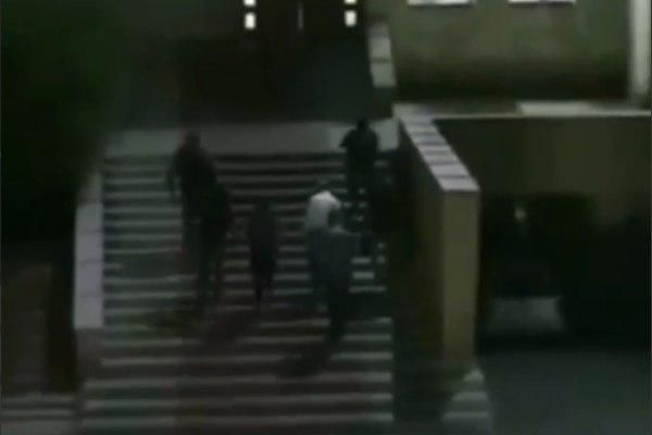 Атамбаев поднимается по лестнице здания под охраной шести человек.