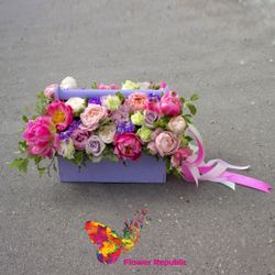 O cutie elegantă din lemn plină cu flori într-o schemă de culoare roz-lavandă